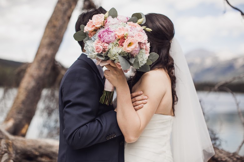 bride and groom kissing. bride carrying a spring garden roses bouquet 