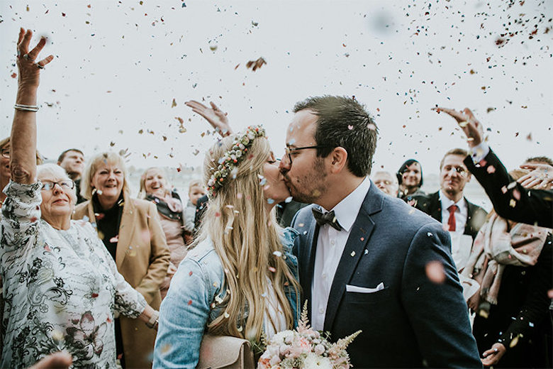 bride and groom kissing under confetti poppers for spring wedding's grand exit