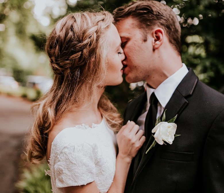 bride and groom kissing. bride's hair in a milkmaid braid. 