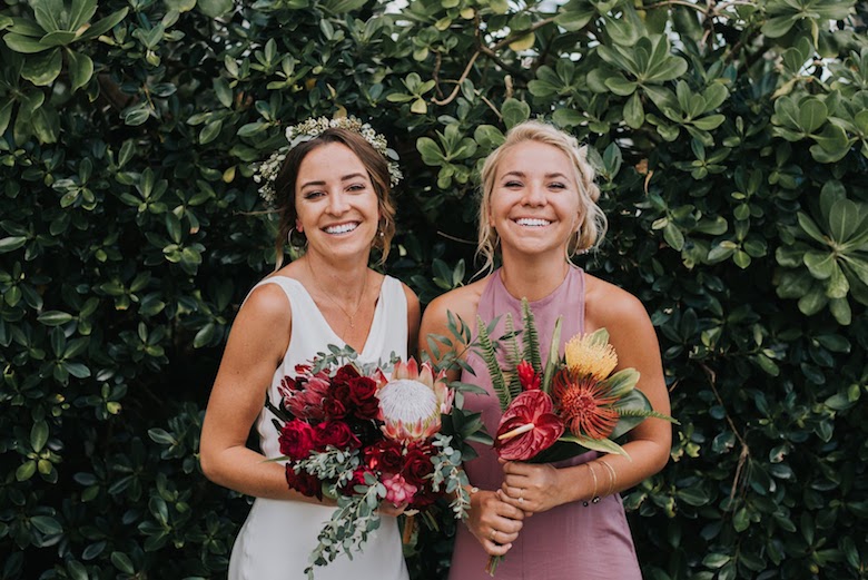 bride and maid of honor carrying tropical flower bouquets