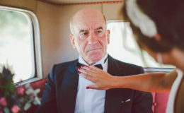 father of the bride getting his bowtie adjusted by his daughter, he looks stern but happy