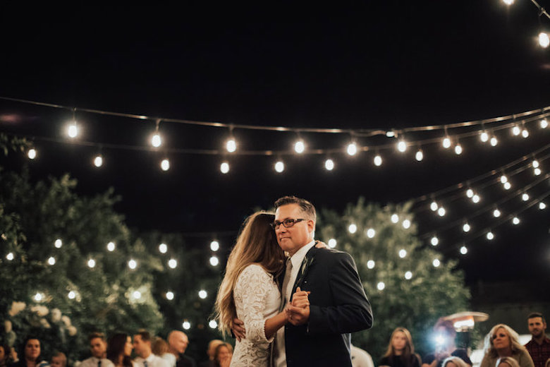 father and daughter dancing outside at an outdoor wedding, lovely stringed lights hanging above them, nice environment