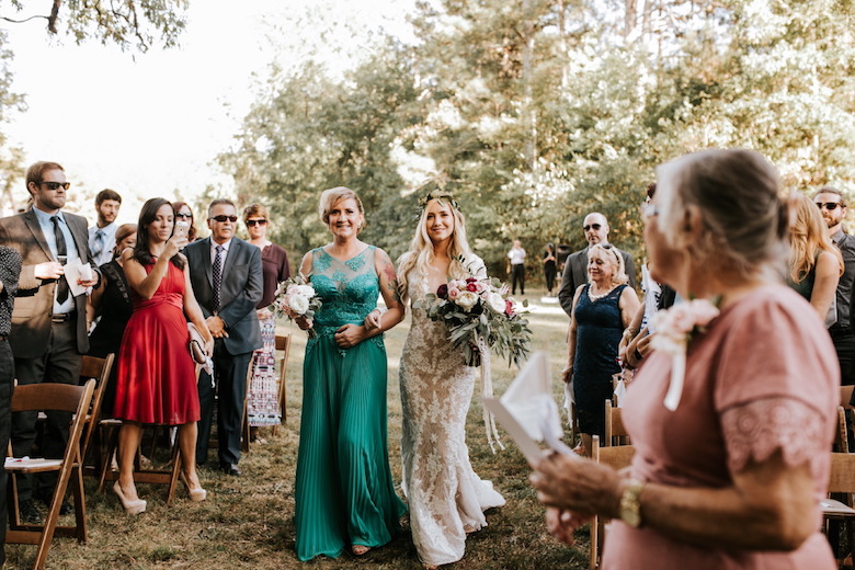 mother wearing green dress walking her daughter down the aisle