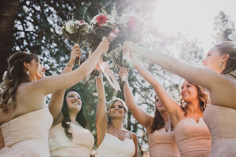 bride and bridesmaids raising bouquets to the sky