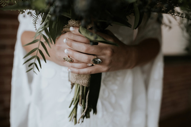 bride holding bouquet wearing non-traditional wedding ring