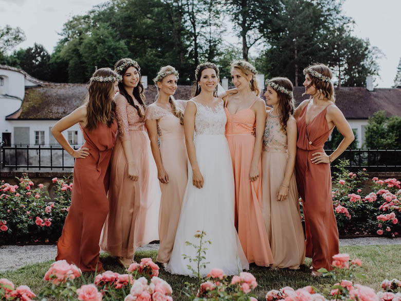 bride surrounded by bridesmaids wearing various dresses
