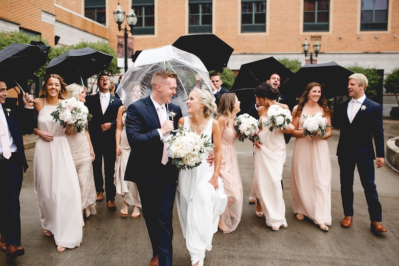 wedding guests holding umbrellas watching bride and groom embrace