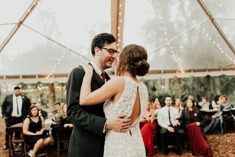 bride and groom share their first dance with guests watching