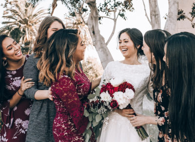 bridesmaids and bride laughing with bouquet