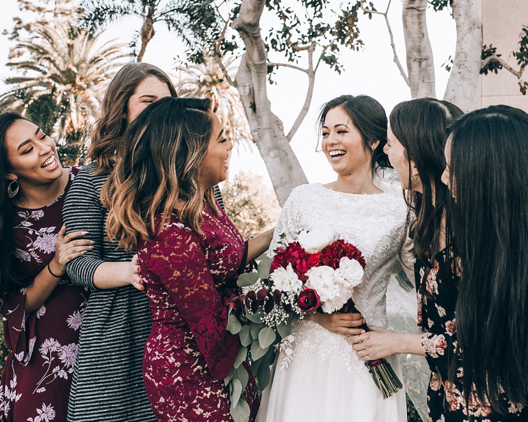 bridesmaids and bride laughing with bouquet