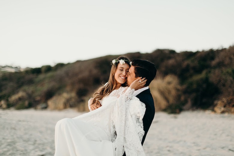 bride and groom holding each other and smiling at beach wedding