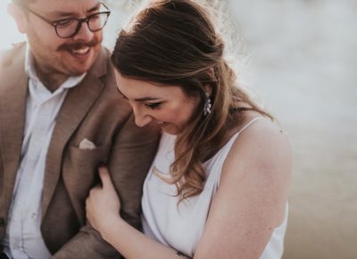 bride and groom with glasses embrace each other and smile