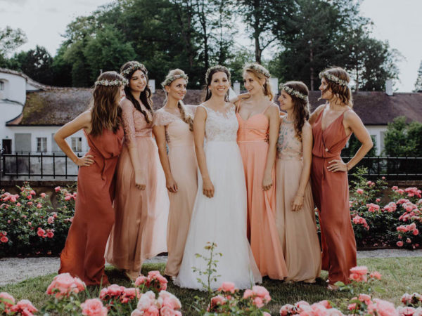 the bride with her six bridesmaids, standing and smiling outside, sunny day