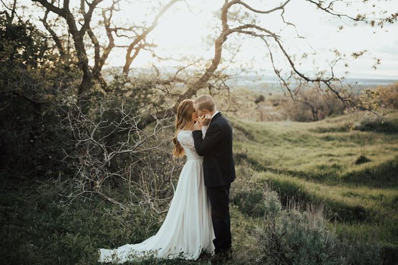 bride and groom kissing near a tree at dawn