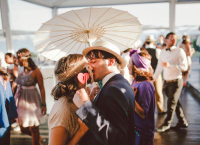 couple kissing under paper parasol at summer wedding