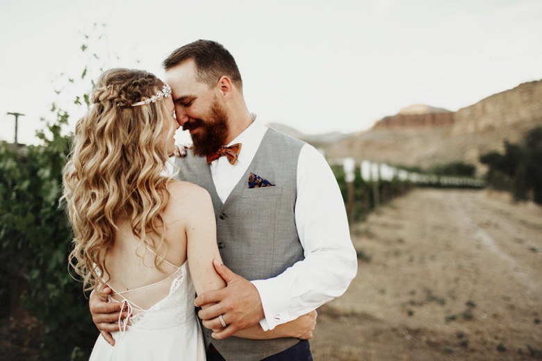 bride and groom embrace each other outside near a canyon in the desert