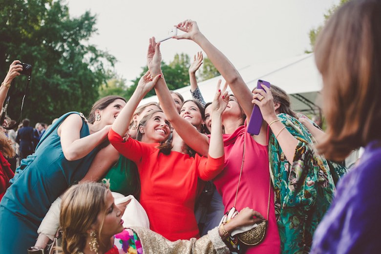 wedding guests gather outside to take a group selfie