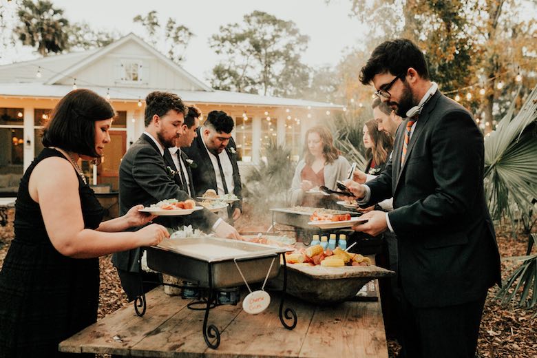wedding guests putting food on their plate at a food station outside