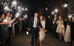 bride and groom exit the venue while wedding guests celebrate with sparklers