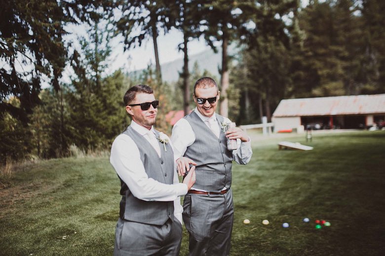 two groomsmen laughing while playing a party game outside