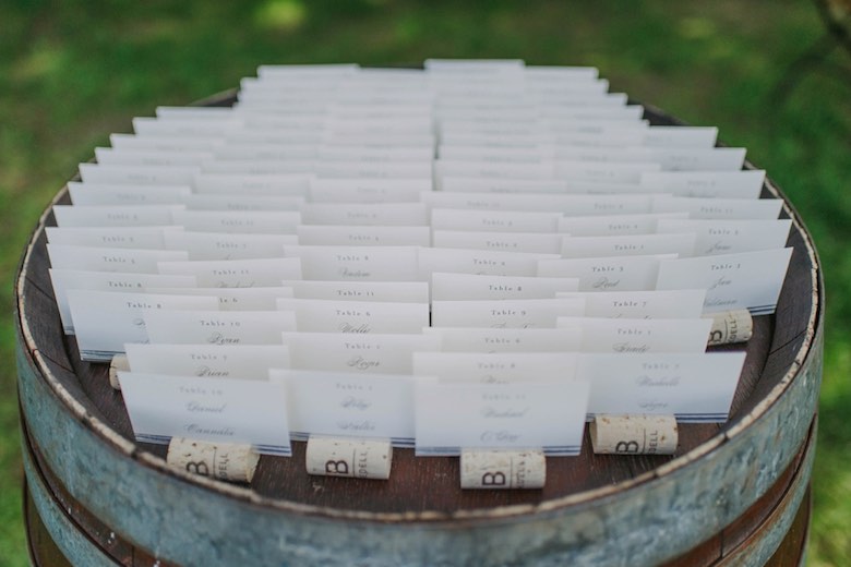 wedding seating cards laid out on a wooden barrel