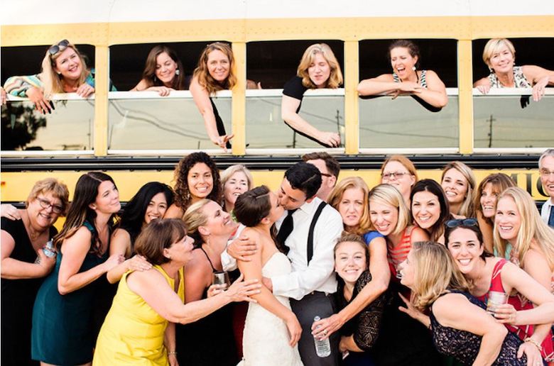 wedding guests crowded around a bus