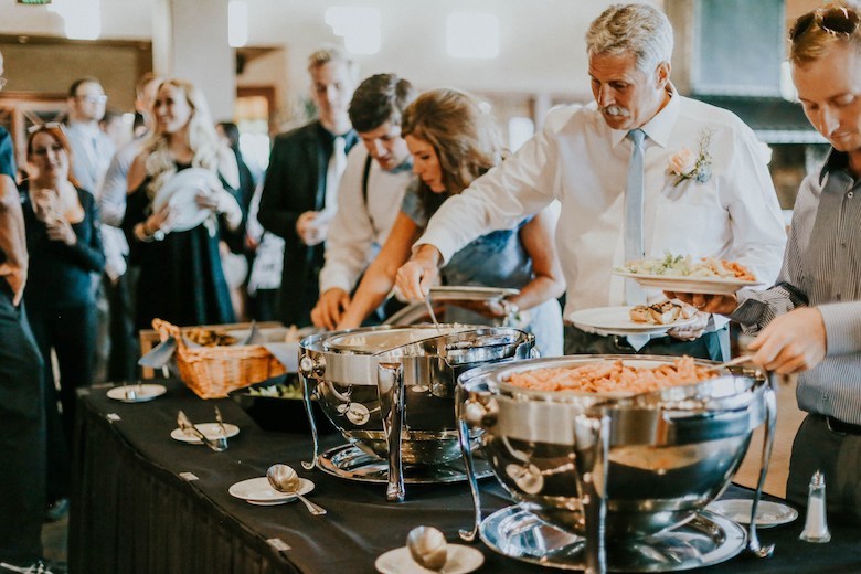 guests grabbing food at a buffet style wedding rehearsal dinner