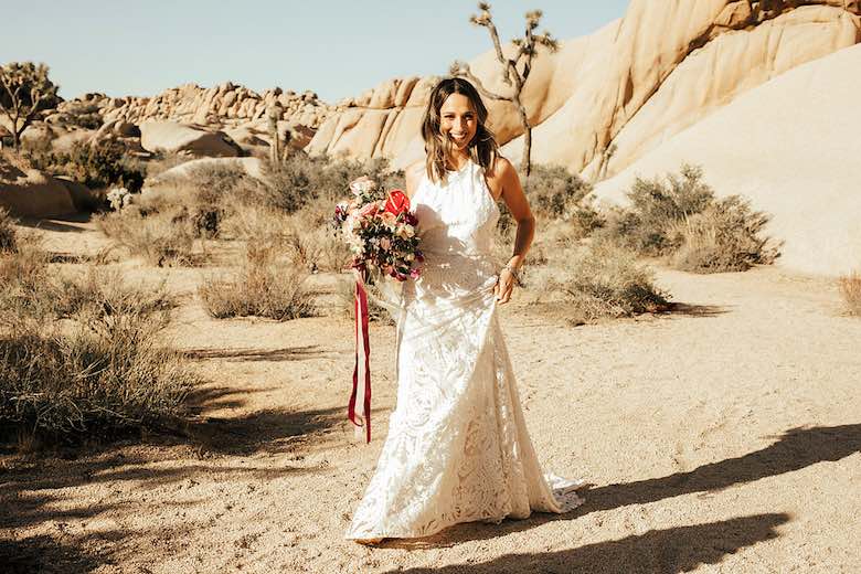 bride in wedding dress holding flower bouquet in the desert