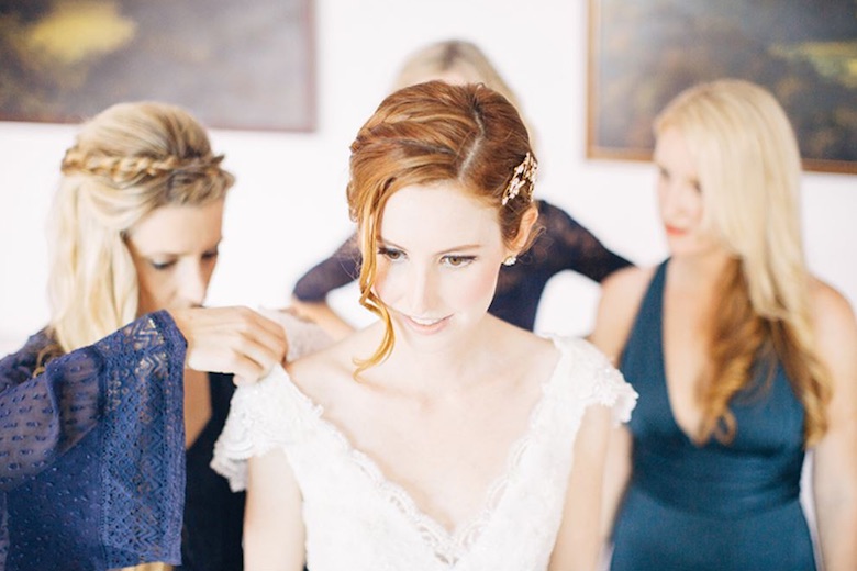 a bridesmaid helps the bride fix her dress