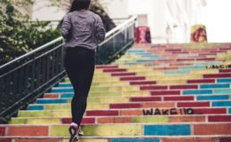 women in workout clothes running up multi-colored stairs with graffiti