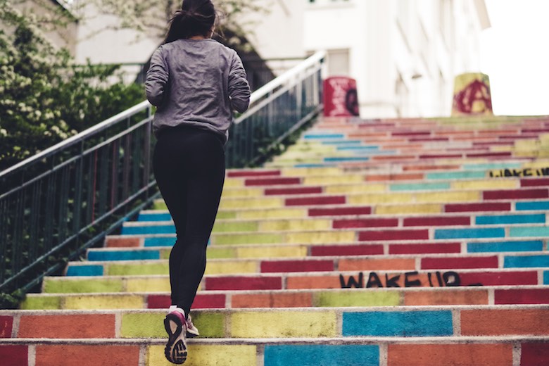 women in workout clothes running up multi-colored stairs with graffiti 